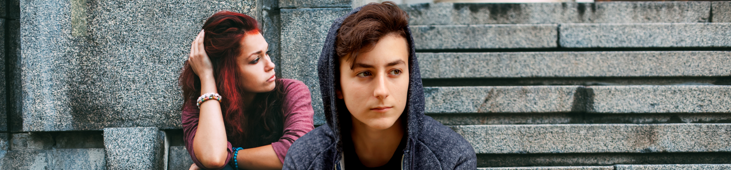 Ein Foto von Jugendlichen auf grauen Steintreppen. Sie sehen betrübt aus.